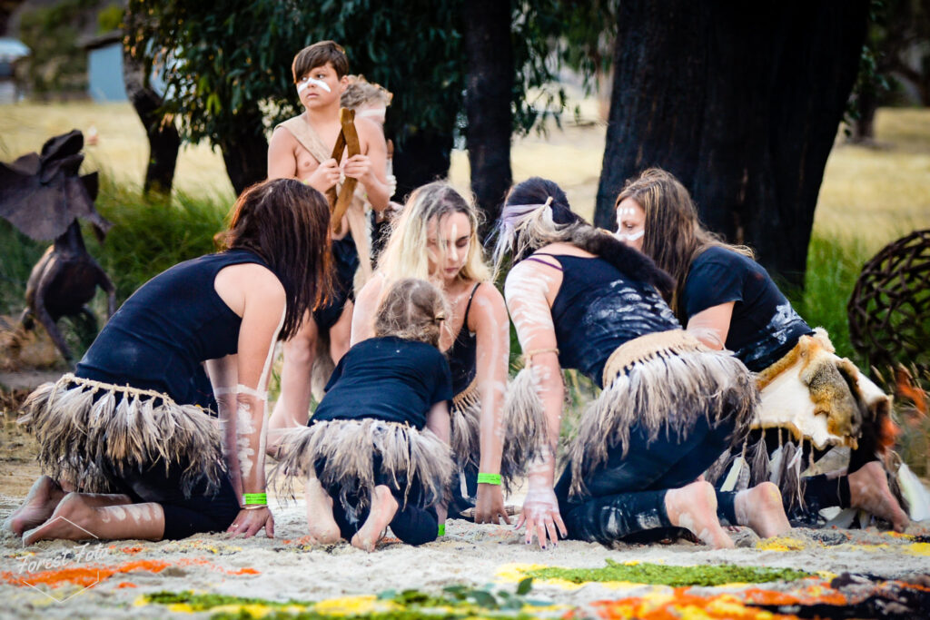 

A group of teenagers is grass skirts making a mandala