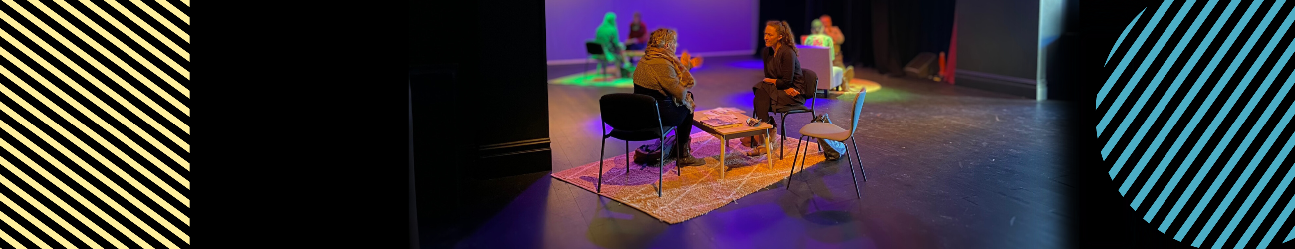 3 tables of two people talking on a stage area with purple and yellow lighting.