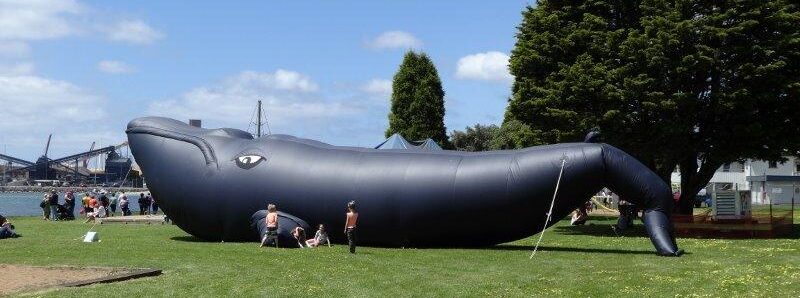 Giant inflatable whale on green grass