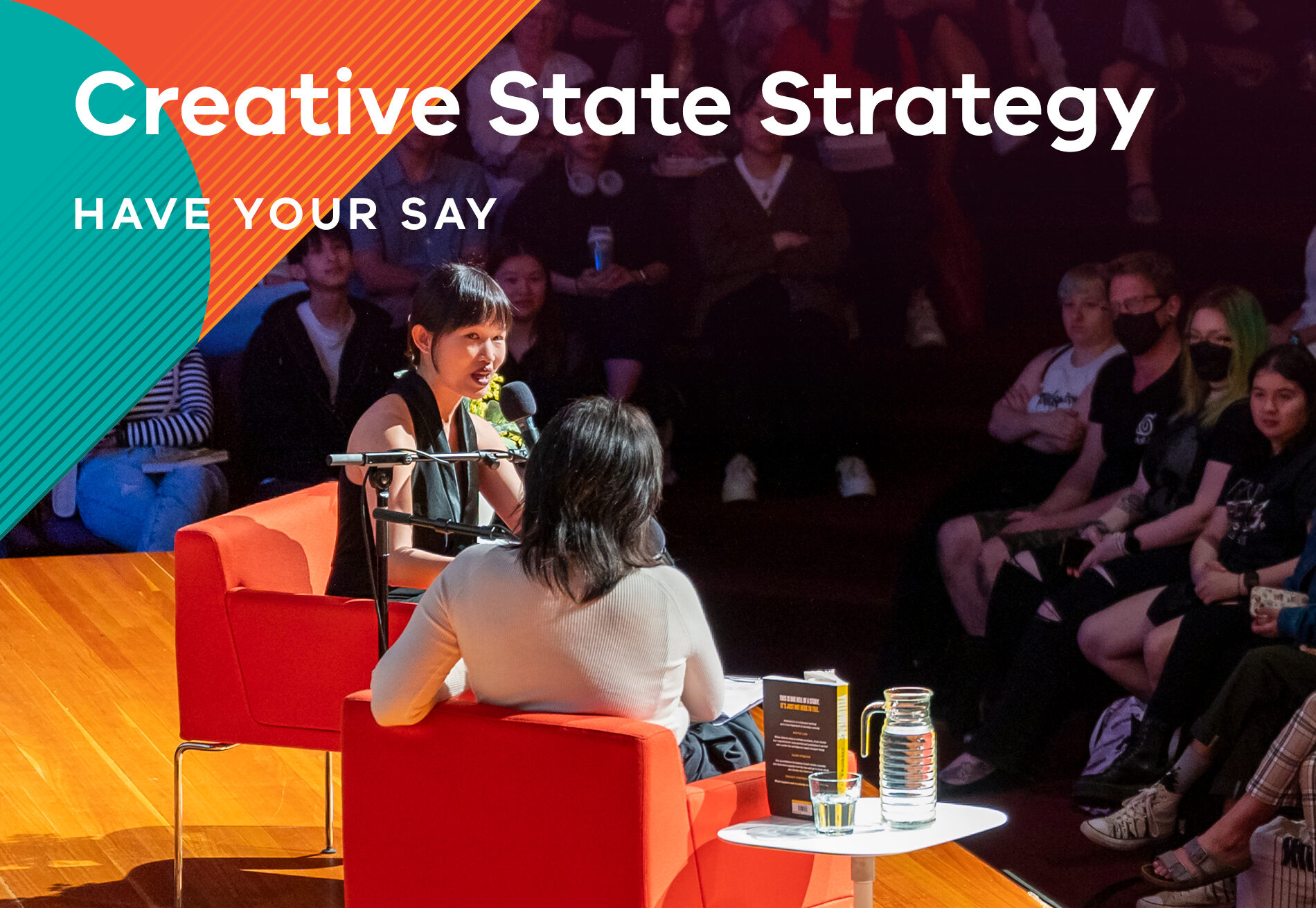 Text: Creative State Strategy, have your say. Photo of two people talking on stage with the audience looking on.