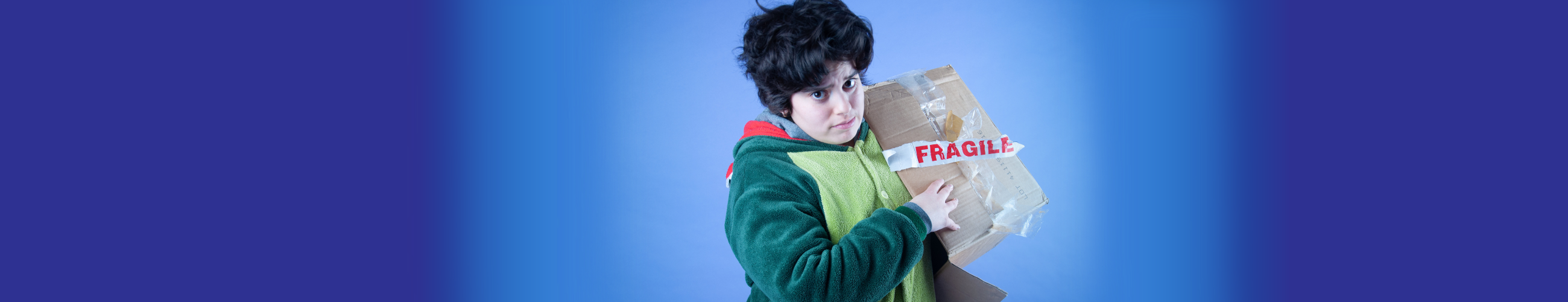 Person in a green onesie holding a carboard box with a fragile sticker on it.