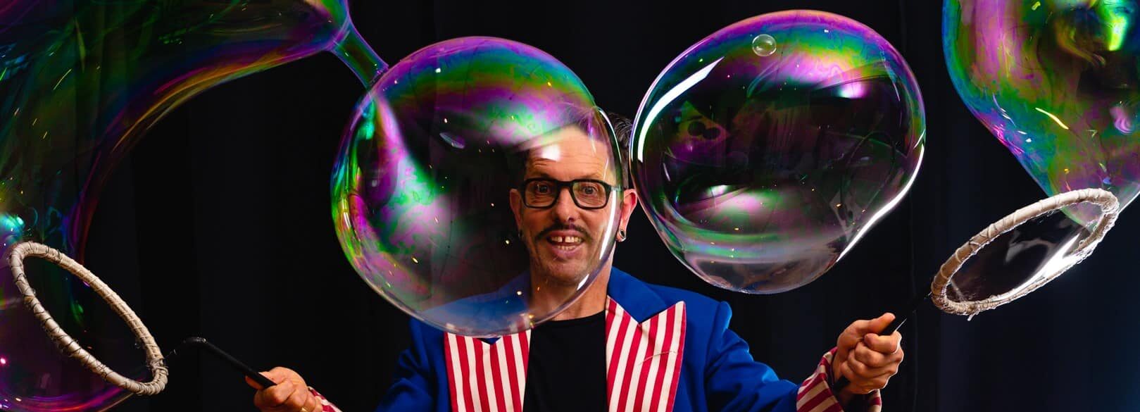 Man surrounded by large bubbles.