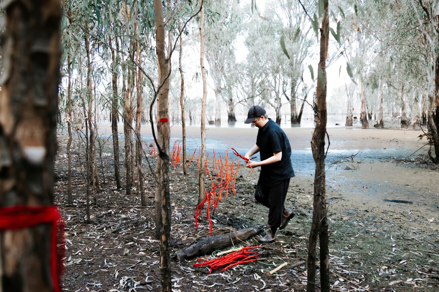 a person placing red sticks by a river.