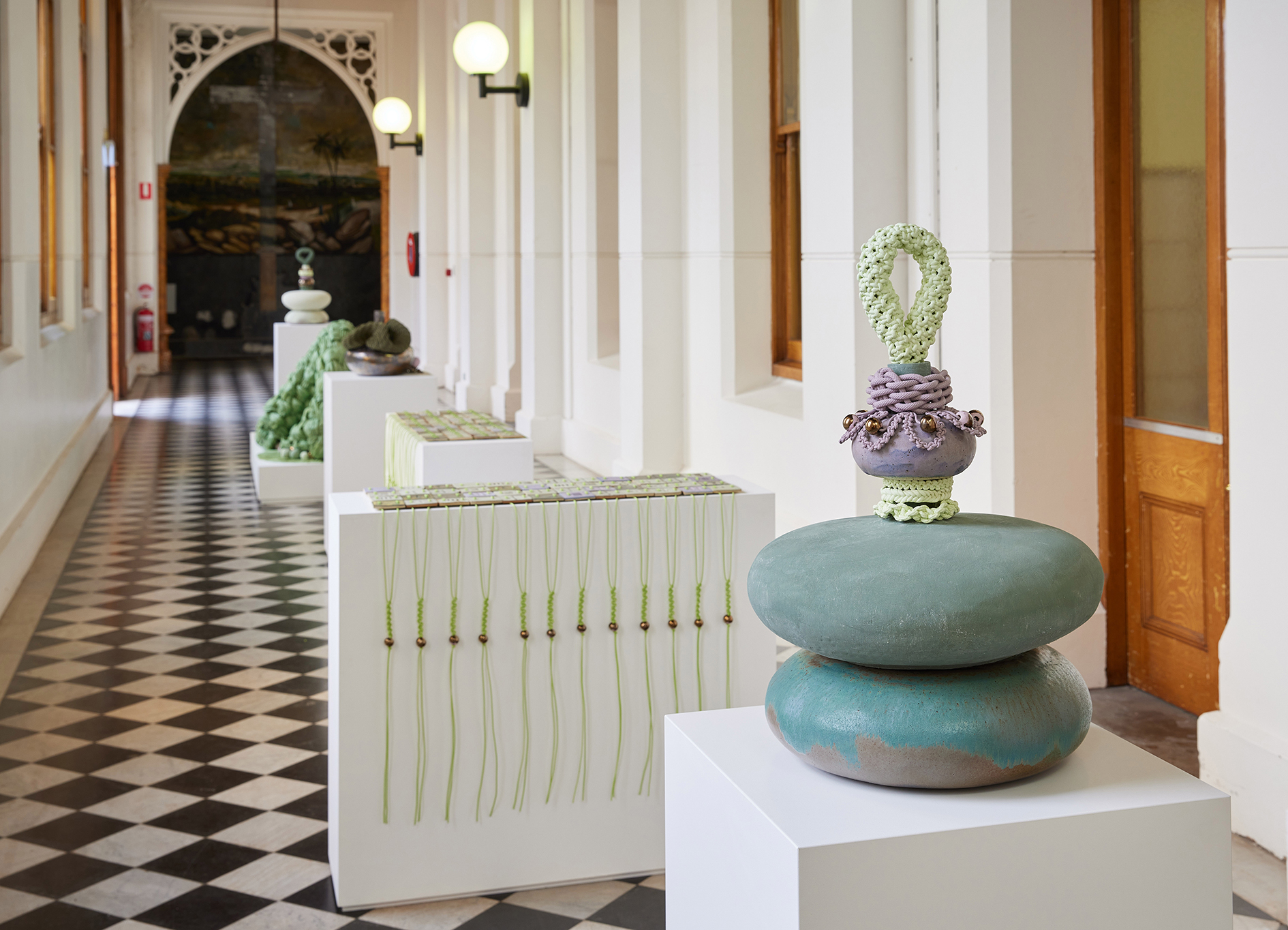 Sculptures in a long hall with checked flooring 